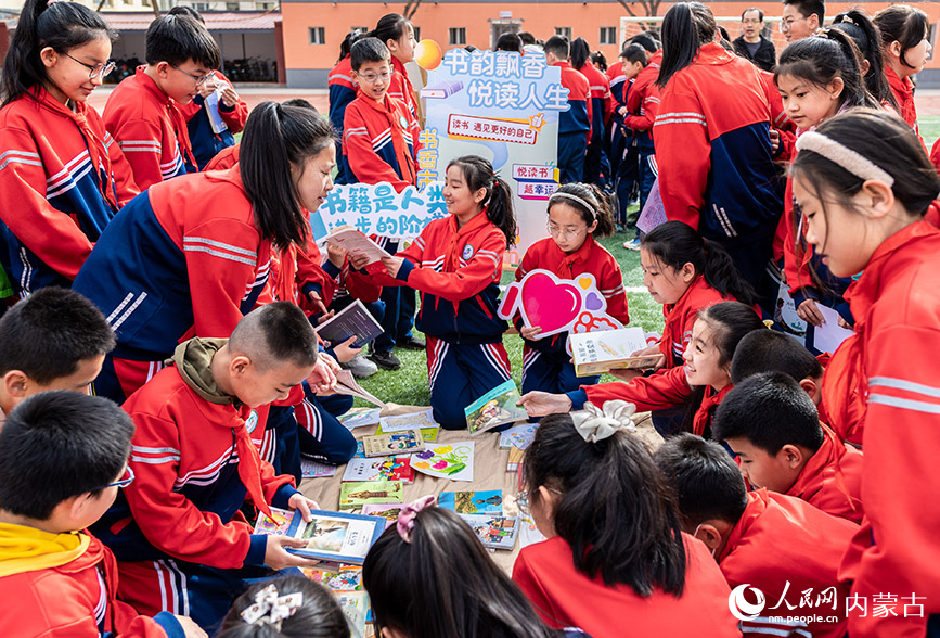 4月17日，呼和浩特市玉泉区南茶坊小学学生在“图书漂流”集市上挑选喜爱的图书。丁根厚摄