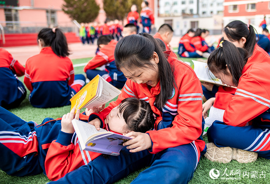 4月17日，呼和浩特市玉泉区南茶坊小学学生在“图书漂流”集市上交换到喜爱的图书后，开心地读书。丁根厚摄