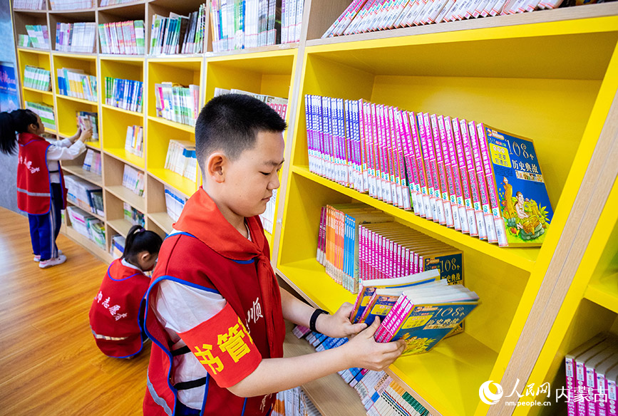4月19日，呼和浩特市玉泉区通顺街小学“小小图书管理员”在“图书走廊”里整理图书。丁根厚摄