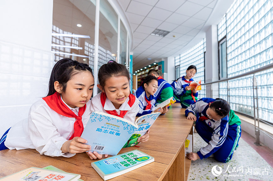 4月19日，呼和浩特市玉泉区通顺街小学学生利用课间休息时间在“图书走廊”阅读专区翻阅图书。丁根厚摄