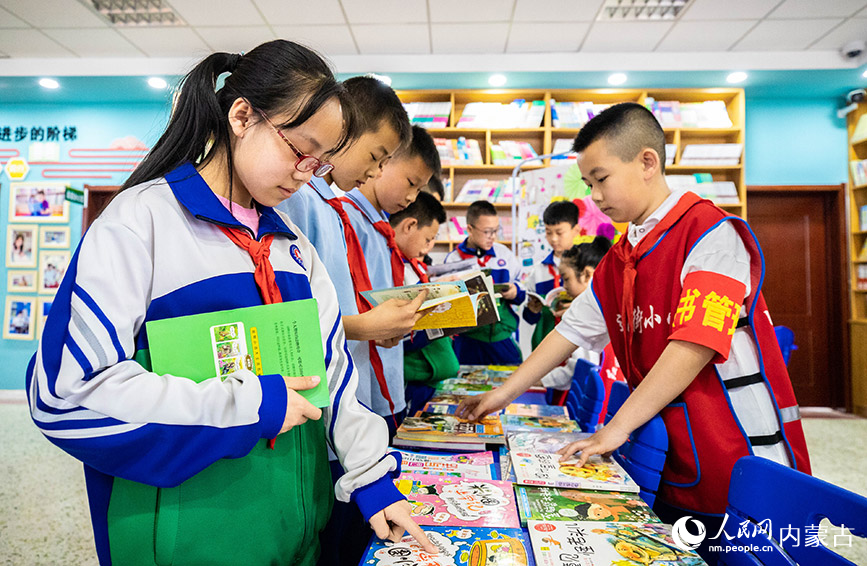 4月19日，呼和浩特市玉泉区通顺街小学学生利用课间休息时间在“图书走廊”共享图书漂流站挑选图书。丁根厚摄