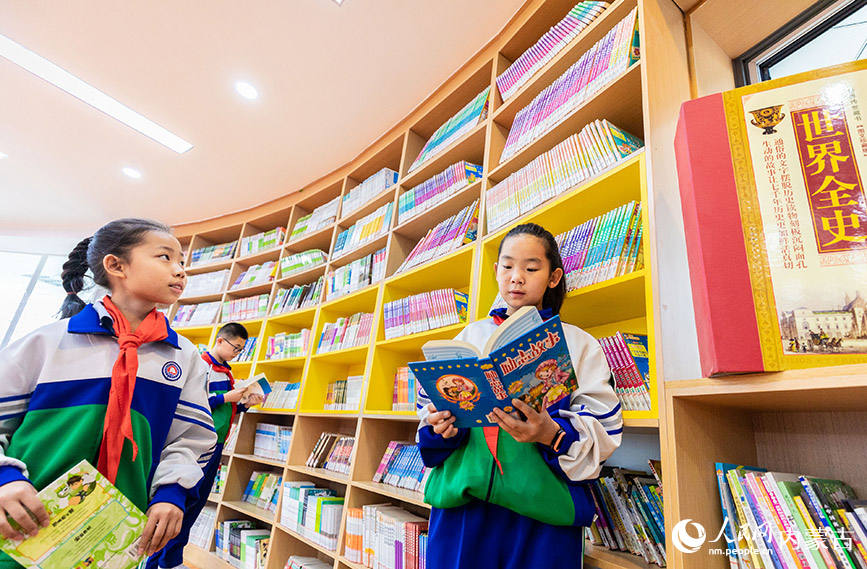 4月19日，呼和浩特市玉泉区通顺街小学学生利用课间休息时间在“图书走廊”翻阅图书。丁根厚摄