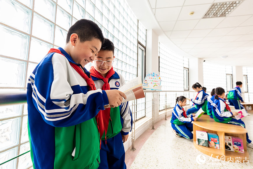 4月19日，呼和浩特市玉泉区通顺街小学学生利用课间休息时间在“图书走廊”阅读区翻阅图书。丁根厚摄