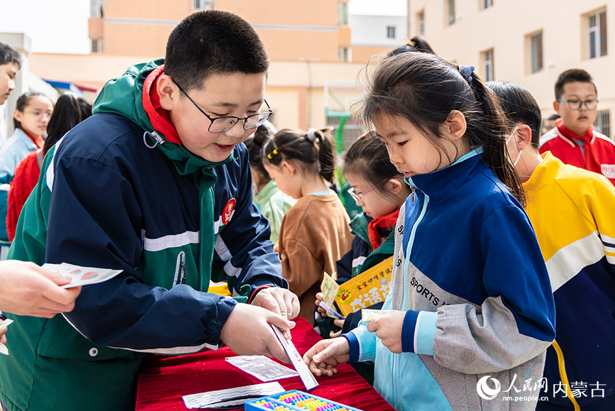 4月21日，呼和浩特市玉泉区恒昌店巷小学学生在“跳蚤市场”上挑选文具。丁根厚摄