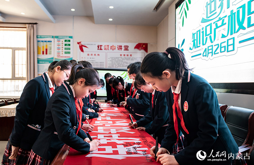 呼和浩特市玉泉区恒昌店巷小学学生在“保护知识产权 人人有责”宣传条幅上签名。丁根厚摄