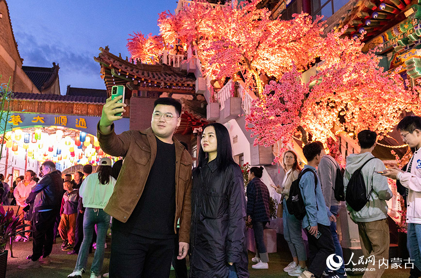 4月30日，游客在呼和浩特市玉泉区塞上老街区块夜市自拍打卡。丁根厚摄