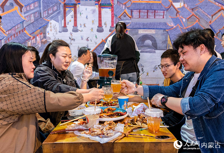 4月30日，游客在呼和浩特市玉泉区塞上老街区块夜市品尝特色小吃。丁根厚摄