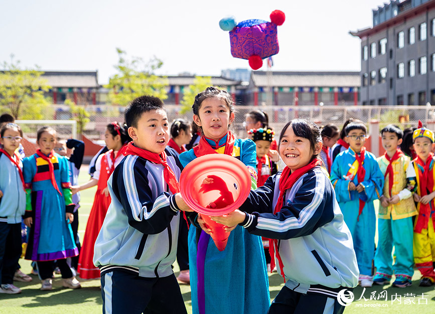5月8日，呼和浩特市玉泉区南柴火市街小学学生在参加三人接沙包比赛。丁根厚摄