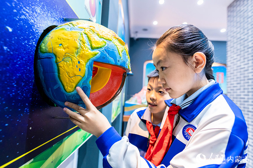 5月11日，呼和浩特市玉泉区通顺街小学学生在地震科普馆里通过模型了解地球内部构造。丁根厚摄