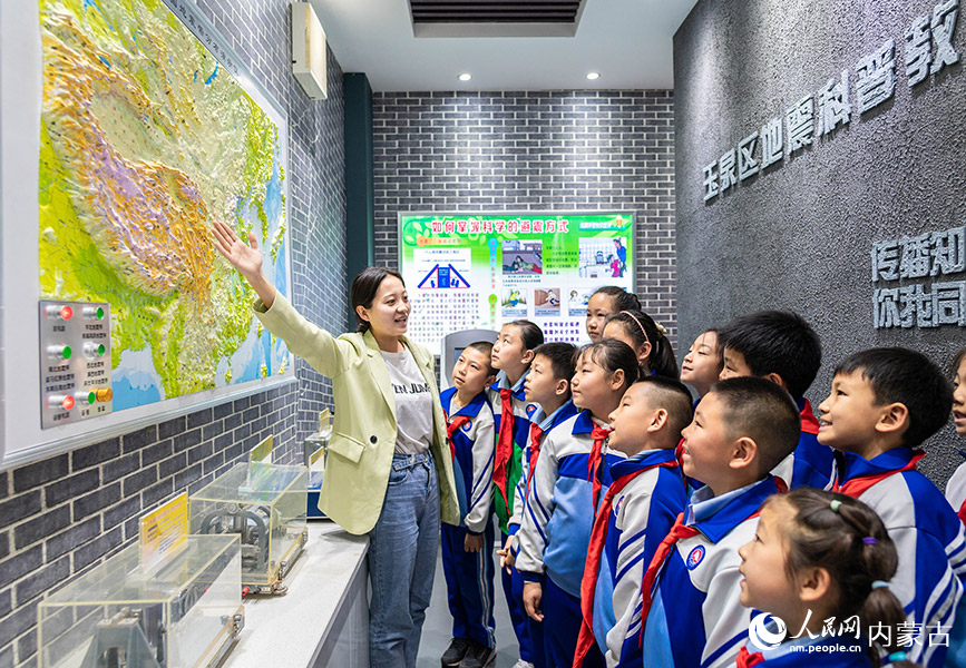 5月11日，呼和浩特市玉泉区通顺街小学教师在地震科普馆通过演示仪向学生讲解中国地震带分布知识。丁根厚摄