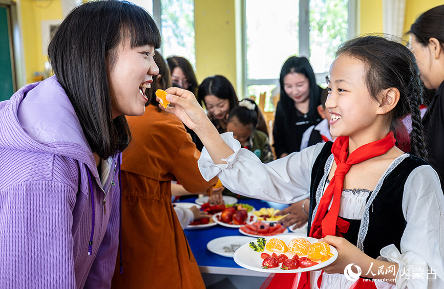 5月12日，呼和浩特市玉泉区五塔寺东街小学学生请妈妈品尝自己刚刚拼好的水果拼盘。丁根厚摄
