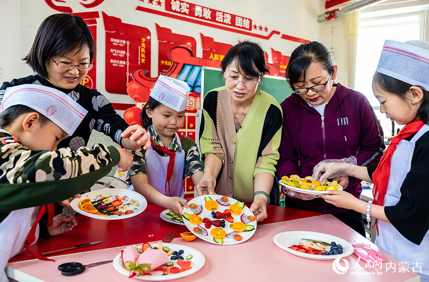 5月12日，呼和浩特市玉泉区五塔寺东街小学学生和妈妈一起制作水果拼盘。丁根厚摄