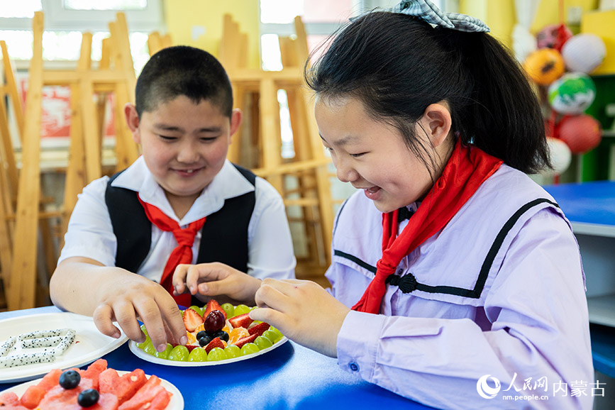 5月12日，呼和浩特市玉泉区五塔寺东街小学学生在制作水果拼盘。丁根厚摄