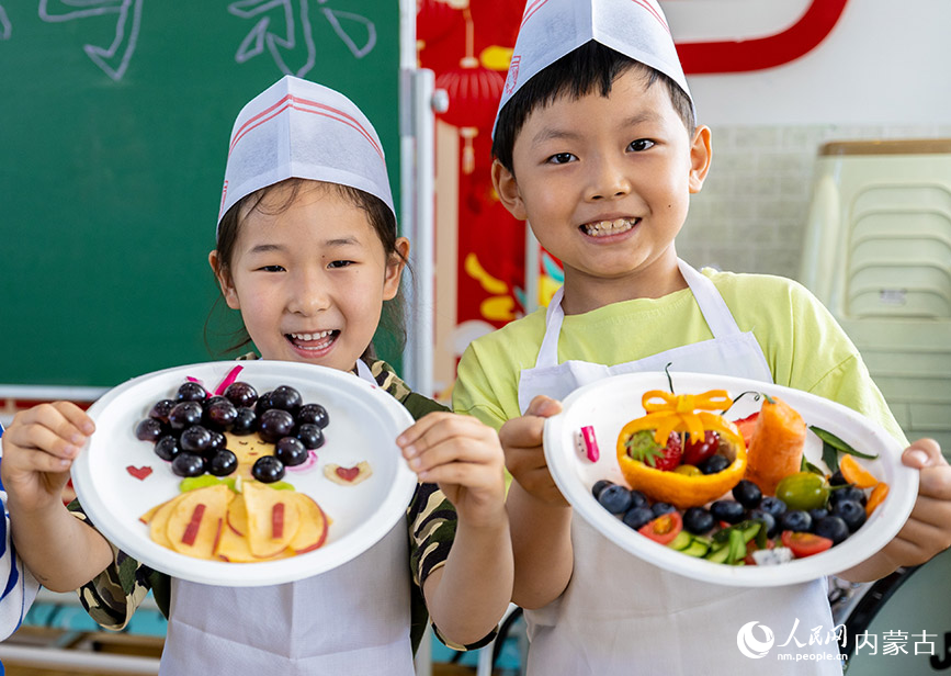 5月12日，呼和浩特市玉泉区五塔寺东街小学学生在展示刚刚拼好的水果拼盘。丁根厚摄