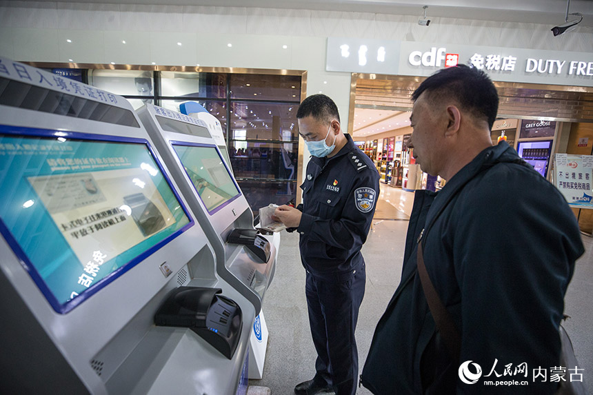 二連出入境邊防檢查站執勤民警為旅客打印通關記錄憑証。胡富國攝