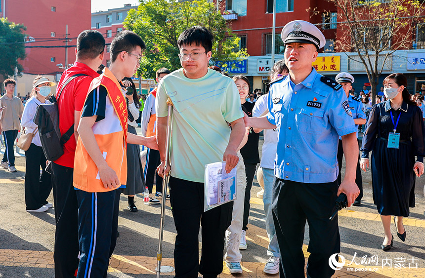 内蒙古呼和浩特市第六中学考点，考务工作人员和志愿者帮助一名腿部受伤的考生进入考场。丁根厚摄