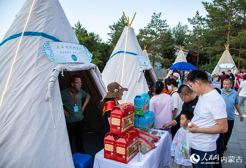 游客在呼和浩特市玉泉区大召历史文化广场“非遗售卖”区品尝风干鸡。丁根厚摄