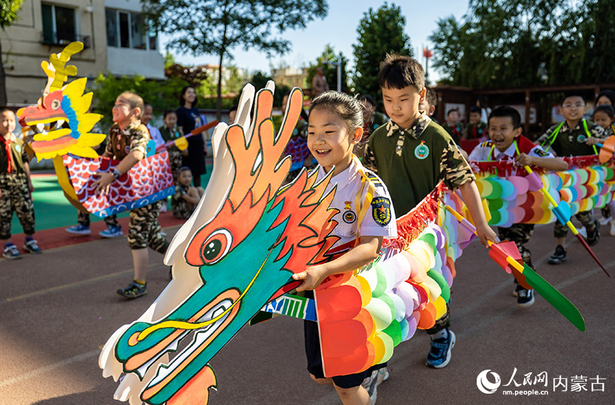 6月20日，内蒙古呼和浩特市玉泉区五塔寺东街小学学生在进行“旱地龙舟”趣味比赛。丁根厚摄
