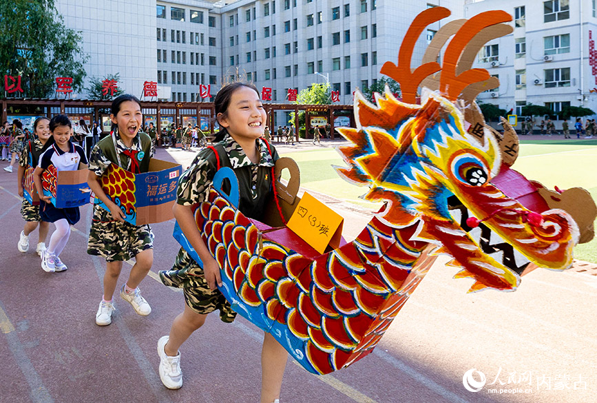 6月20日，内蒙古呼和浩特市玉泉区五塔寺东街小学学生在进行“旱地龙舟”趣味比赛。丁根厚摄