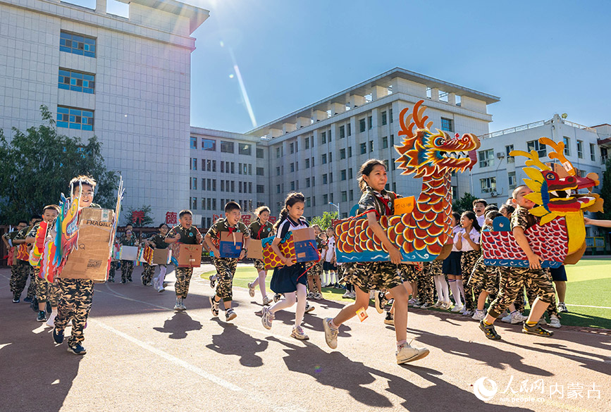 6月20日，内蒙古呼和浩特市玉泉区五塔寺东街小学学生在进行“旱地龙舟”趣味比赛。丁根厚摄