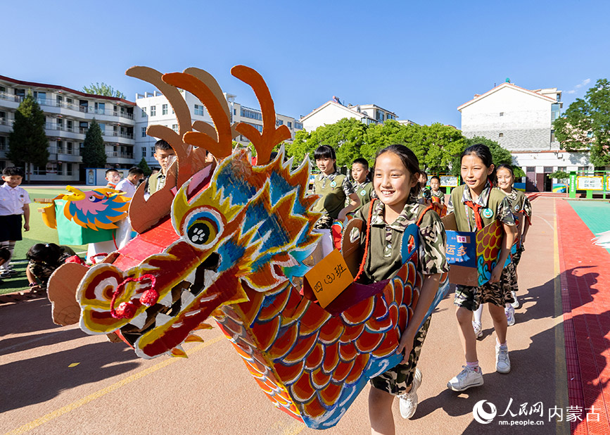6月20日，内蒙古呼和浩特市玉泉区五塔寺东街小学学生在进行“旱地龙舟”趣味比赛。丁根厚摄
