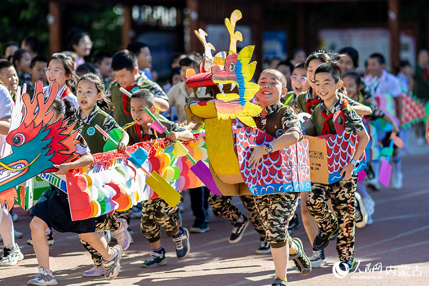 6月20日，内蒙古呼和浩特市玉泉区五塔寺东街小学学生在进行“旱地龙舟”趣味比赛。丁根厚摄