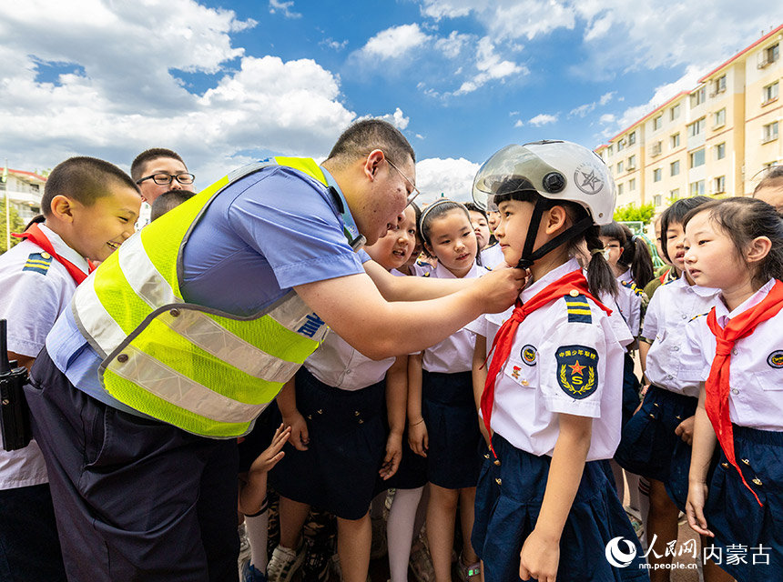 呼和浩特市玉泉区交管大队景区中队民警为学生讲解佩戴头盔的正确方法。丁根厚摄