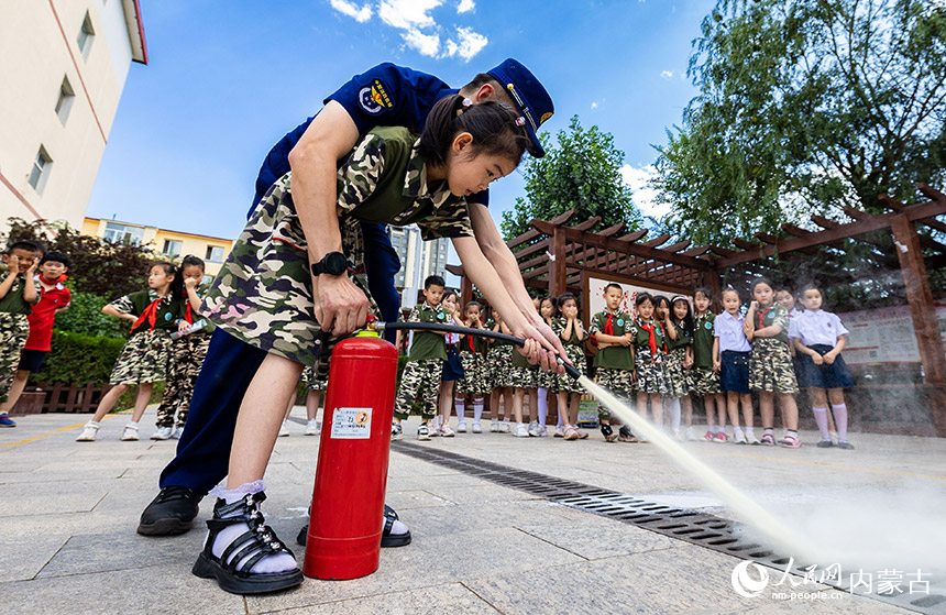 呼和浩特市玉泉区五塔寺东街小学学生在消防员的指导下学习灭火器的使用方法。丁根厚摄