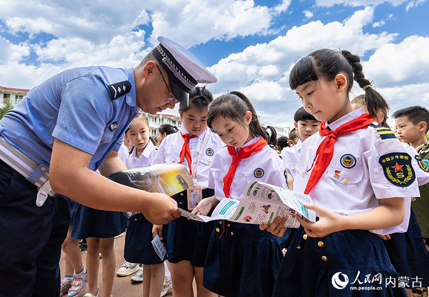 呼和浩特市玉泉区交管大队景区中队民警为学生发放交通安全知识宣传手册。丁根厚摄