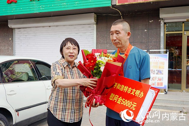 7月24日，呼和浩特市委宣传部副部长、文明办主任张东霞为李子华送上荣誉证书、奖牌、慰问金和鲜花。实习生 李宇琼摄