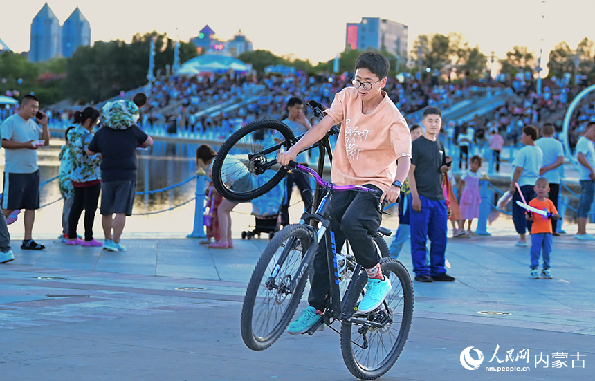 游客在鄂尔多斯市康巴什区乌兰木伦文化和旅游街区夜市里炫车技。王正摄