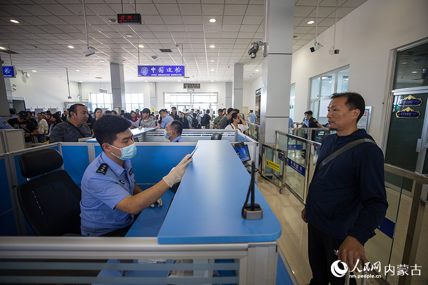 二连出入境边防检查站执勤民警为参加中蒙博览会的旅客办理入境通关手续。郭鹏杰摄