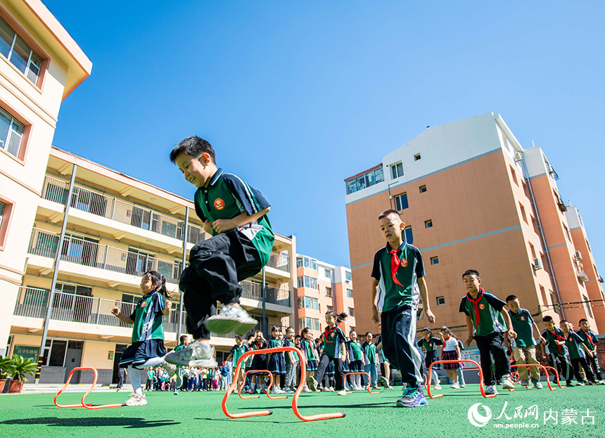 呼和浩特市玉泉区恒昌店巷小学学生在玩“跨越障碍”趣味游戏。丁根厚摄