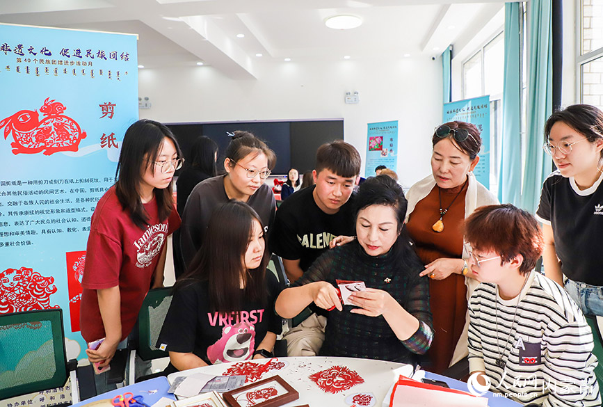 9月20日，非遺傳承人在呼和浩特民族學院為學生們展示剪紙的制作技藝。丁根厚攝