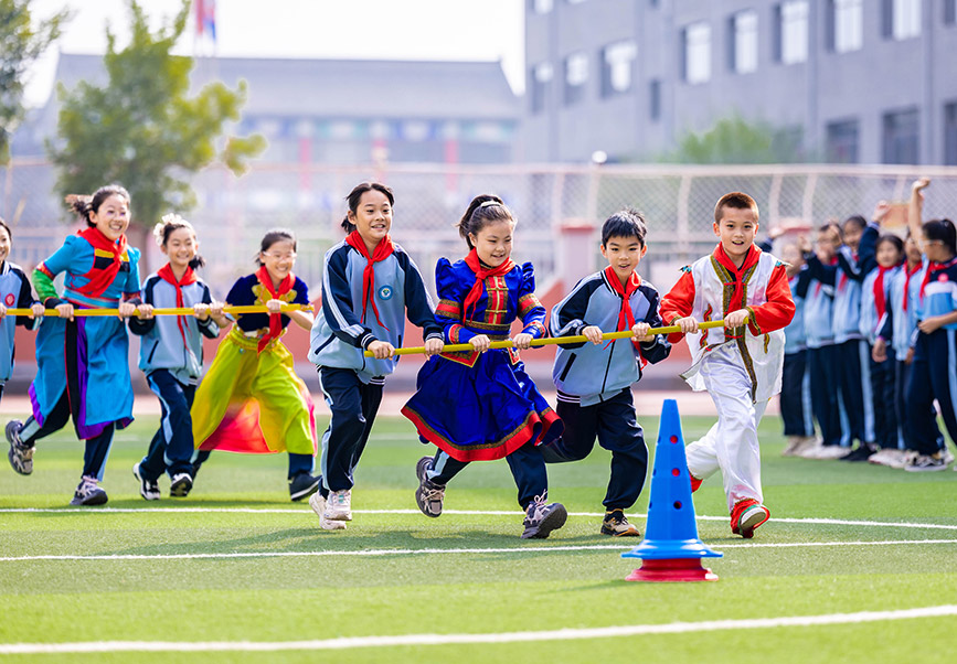 9月25日，呼和浩特市玉泉區南柴火市街小學學生在參加四人繞樁趣跑游戲。丁根厚攝