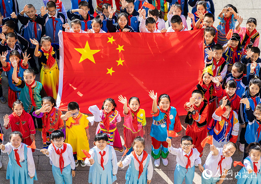 9月26日，呼和浩特市玉泉區清泉街小學學生與國旗合影，為祖國送上祝福。丁根厚攝