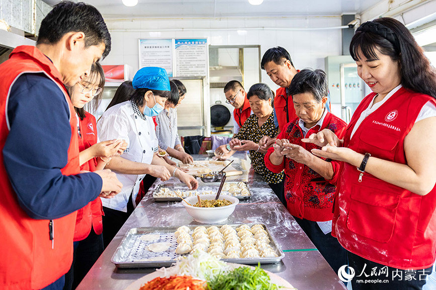 9月28日，內蒙古呼和浩特市玉泉區民政局的黨員志願者在和老人們一起包餃子。丁根厚攝
