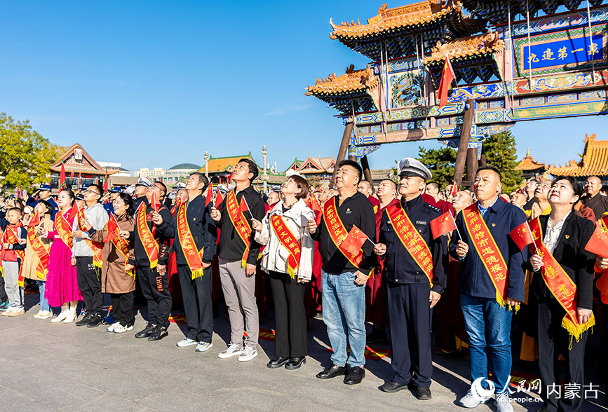 10月1日，道德模范、新时代好少年和最美志愿者等代表在呼和浩特市玉泉区塞上老街文化旅游休闲街区参加国庆节升旗仪式。丁根厚摄