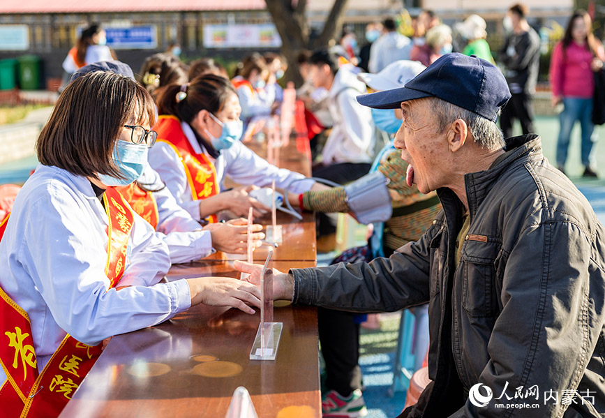 10月18日，内蒙古自治区人民医院第三党总支的医疗专家为社区老人把脉诊疗。丁根厚摄