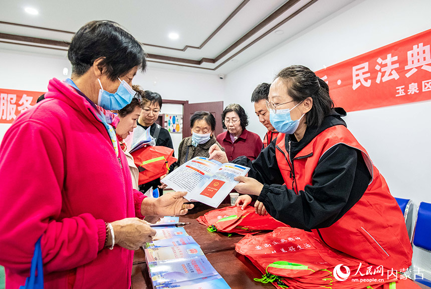 普法宣传志愿者在呼和浩特市玉泉区“我们的节日·重阳节”活动现场向老人进行民法典宣传。丁根厚摄