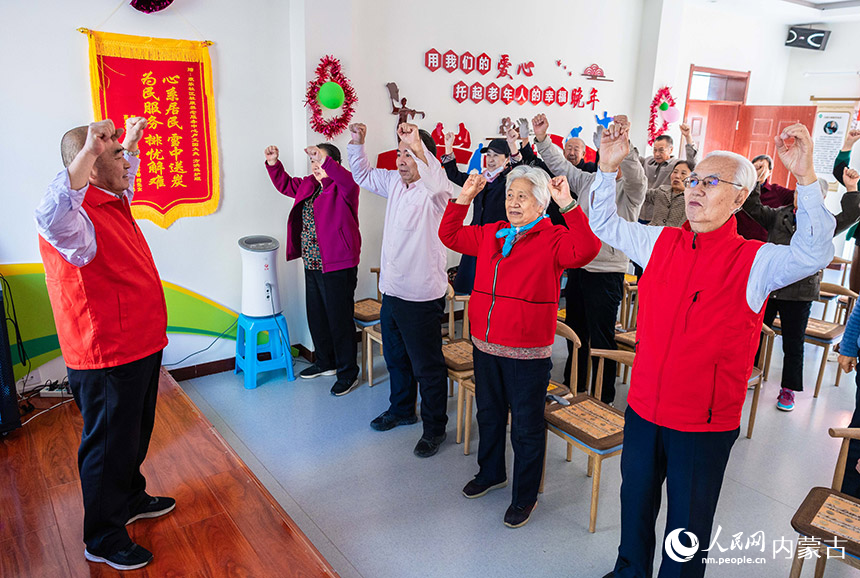 呼和浩特市玉泉区石东路街道居家和社区养老服务综合体，志愿者陪伴老人们练习养生操。丁根厚摄