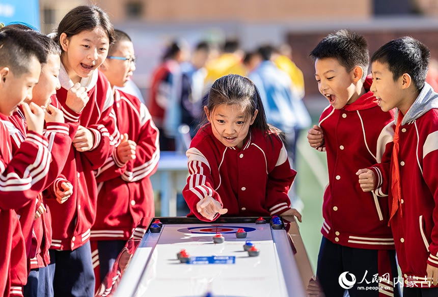 呼和浩特市玉泉区恒昌店巷小学学生在参加“桌面冰壶”游戏。丁根厚摄