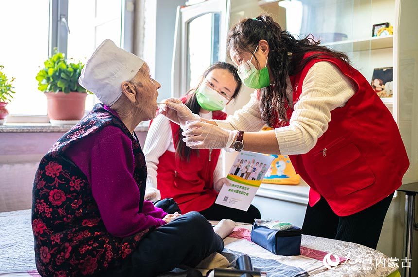 呼和浩特市玉泉区民政局的党员志愿者上门为社区老人吕桂云进行口腔清洁护理服务。丁根厚摄