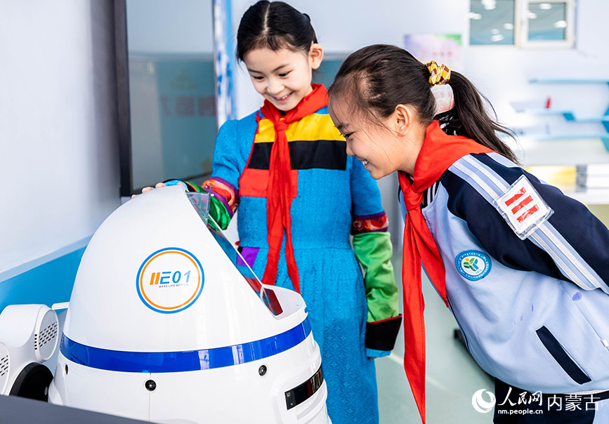 11月30日，呼和浩特市玉泉区南柴火市街小学学生与机器人“小胖”互动。丁根厚摄