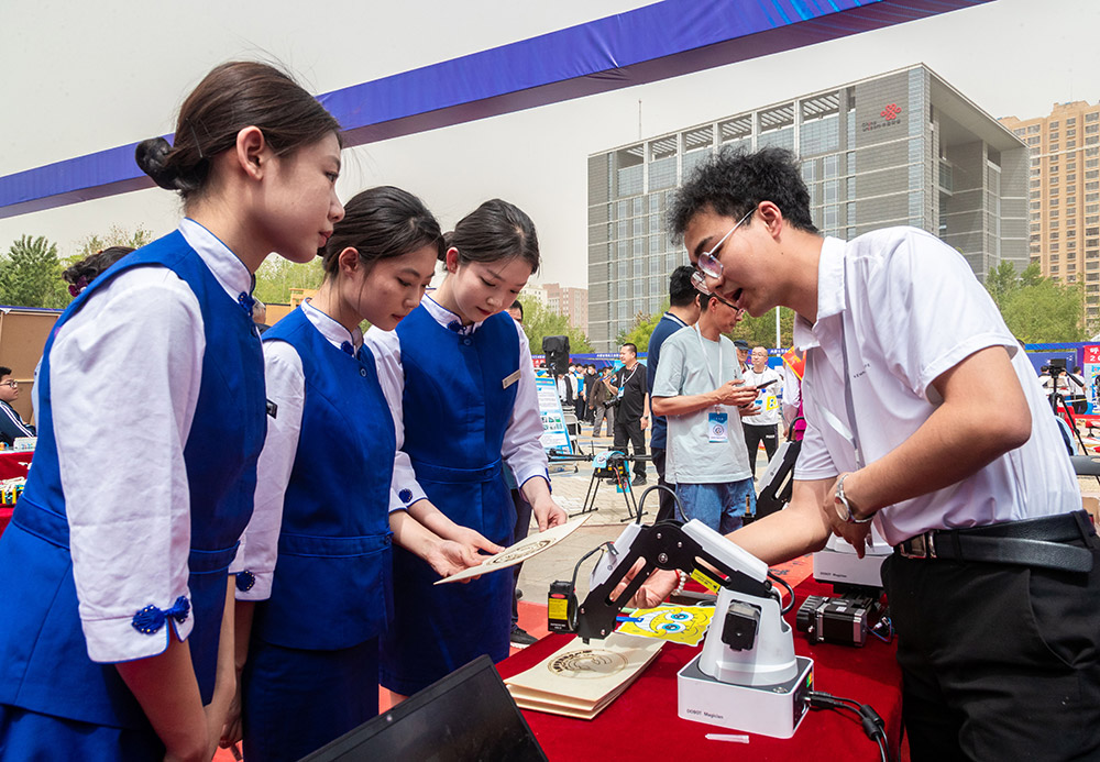 中职学生在呼和浩特市2023年职教活动周暨“未来工匠”读书行动启动仪式现场展示激光雕刻工业机器人。