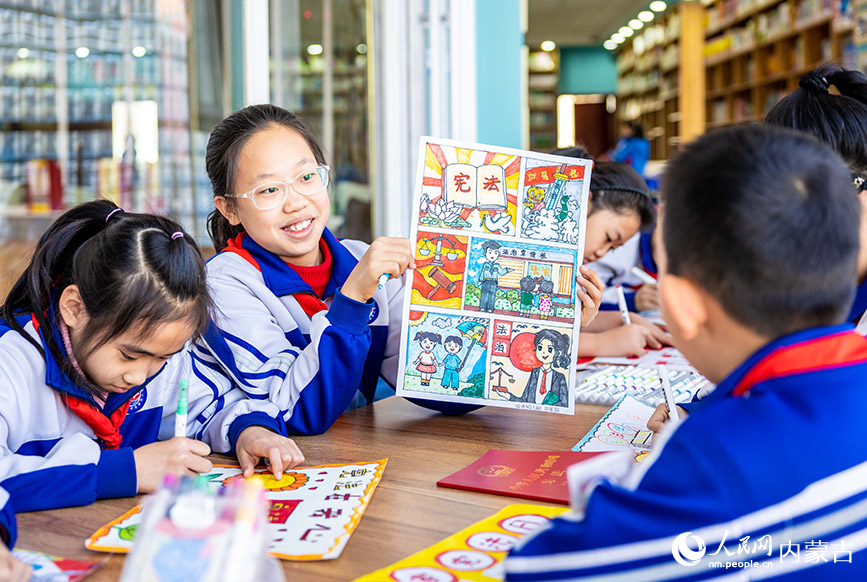 12月4日，呼和浩特市玉泉区通顺街小学学生在展示绘制的以国家宪法日为主题的手抄报。丁根厚摄