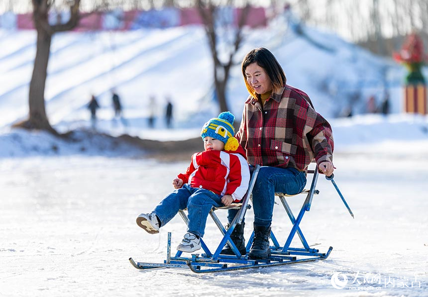 家长陪伴孩子在呼和浩特市玉泉区大库伦村“冰雪大世界”内体验滑冰车。丁根厚摄