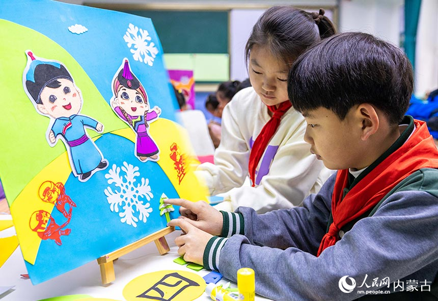 呼和浩特市玉泉区小召小学学生在绘制“十四冬”吉祥物“安达”和“赛努”手工作品。丁根厚摄