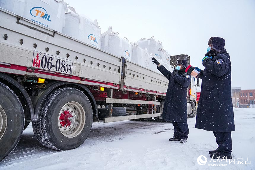 二连出入境边防检查站移民管理警察顶风冒雪查验通关车辆。杨金烨摄