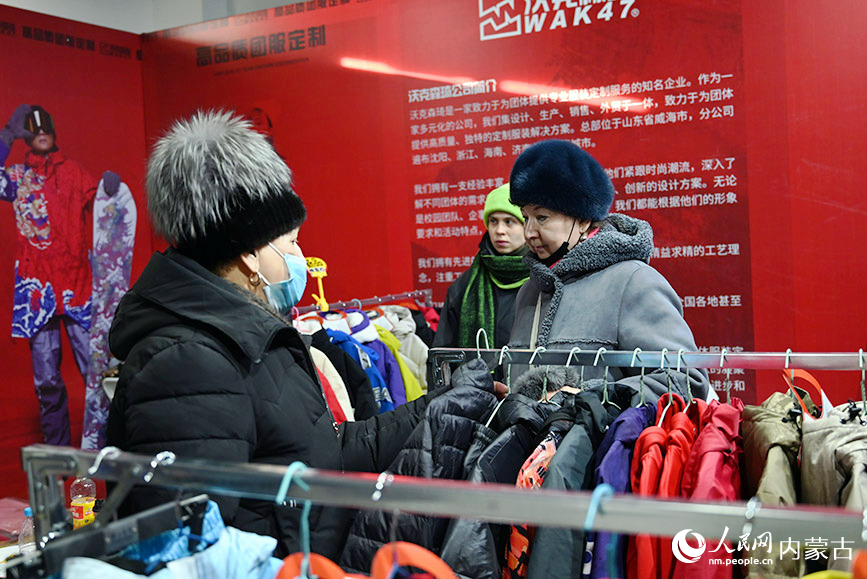 来自俄罗斯的游客在首届呼伦贝尔·海拉尔冰雪产品冬季展销会现场挑选衣服。人民网记者 刘艺琳摄